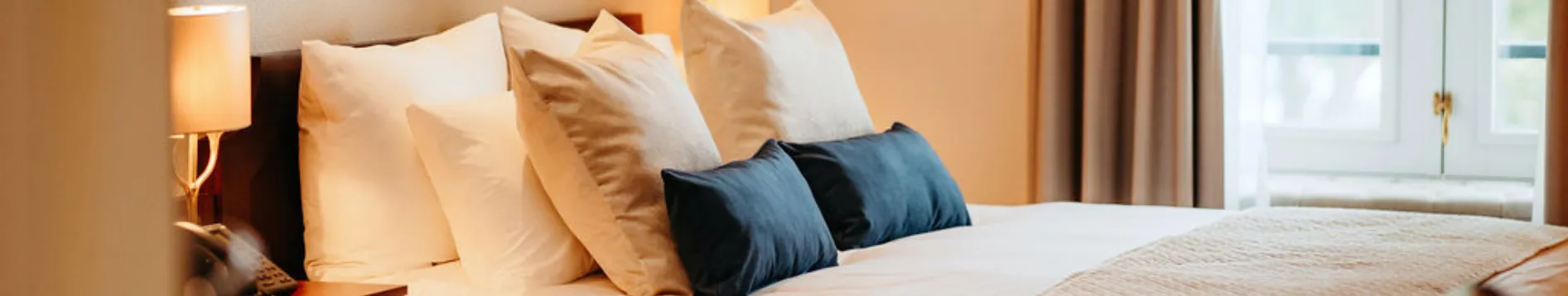 Luxe hotelkamer met kingsize bed en blauwe kussens

